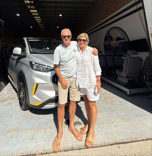 Two people standing in front of a car in a showroom