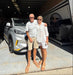 Two people standing in front of a car in a showroom