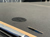 Close-up of a textured surface with a circular black object and metallic edge.
