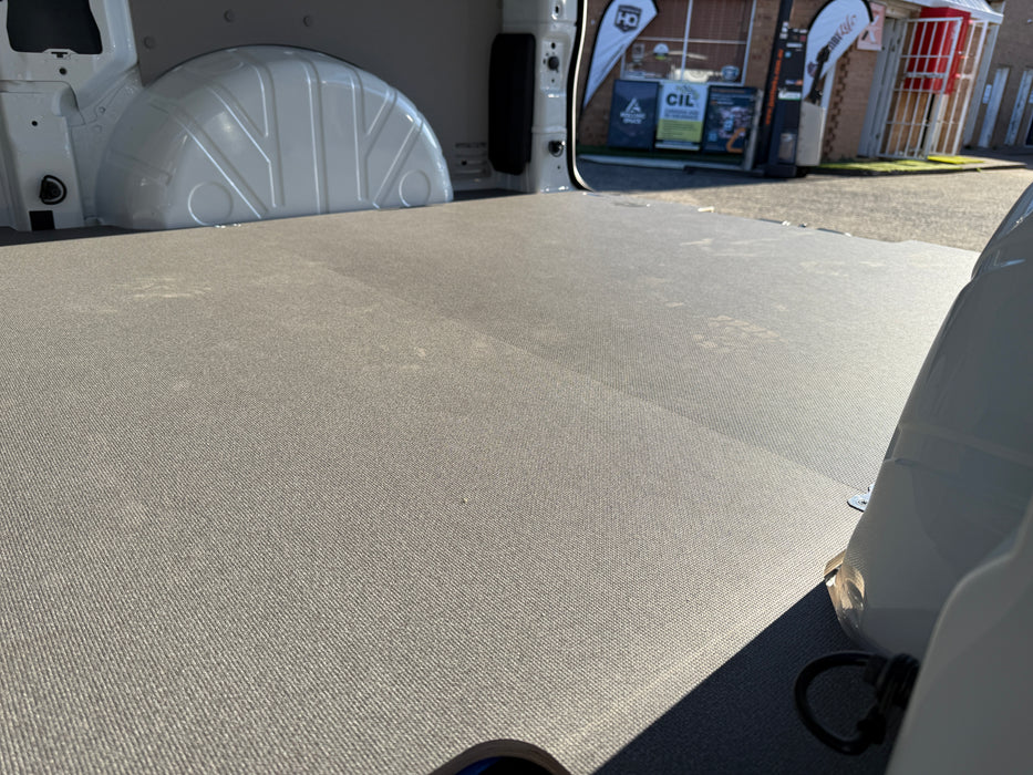 Gray cargo area of a vehicle with a building and signs in the background