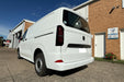 White van parked in front of a building with a blue sky.