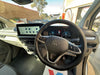 Car interior with steering wheel and dashboard, showing a Volkswagen logo.