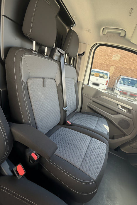 Gray car interior with quilted seat covers and a view of the outside through the window.