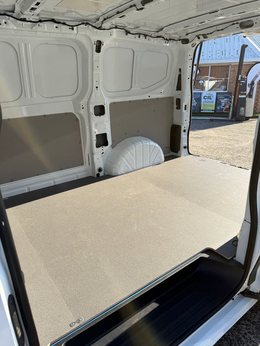 Van interior with a flatbed and open door, showing a building exterior in the background.